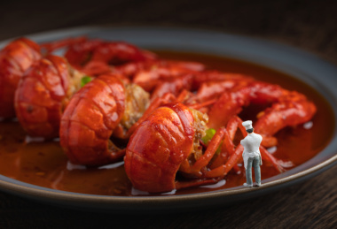 木桌上盘子里的麻辣小龙虾与厨师