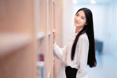 漂亮的女生站在图书馆书架前