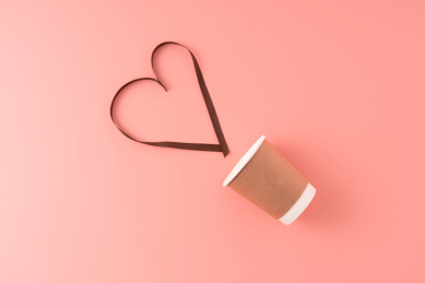 简约的牛皮纸杯与爱心形状的丝带,粉色背景