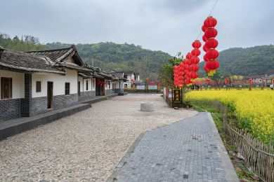 乡间特色建筑及其前面的空地和油菜花