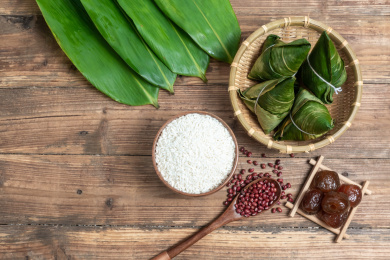 木纹背景上放着的新鲜粽子以及包粽子食材