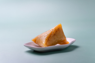 青色背景上的小碟子装着一个剥开的粽子