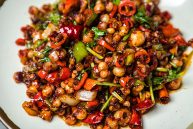 暗色水泥纹桌上放着一盘辣炒海灵菇