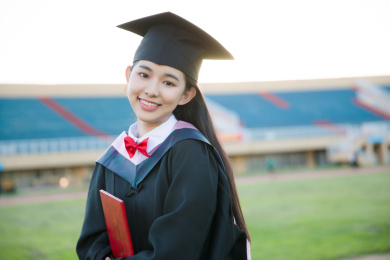 穿着学士服的毕业生手拿毕业证微笑