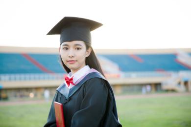 穿着学士服的毕业生手拿毕业证微笑