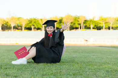 大学生坐在草坪上挥手告别