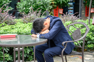 职场男性趴在公园的桌子上休息