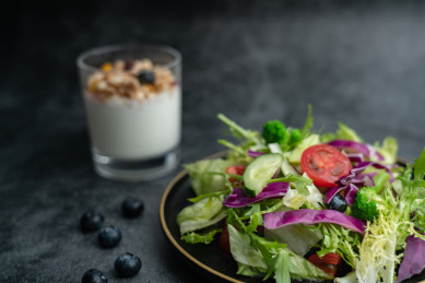 一盘沙拉和一杯燕麦牛奶在灰水泥地上
