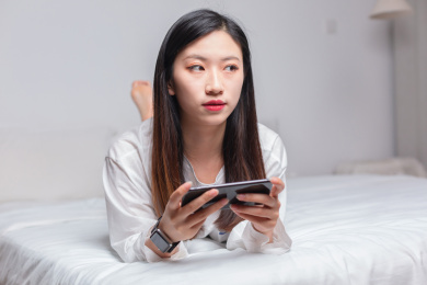 趴在床上玩手机的亚洲美女