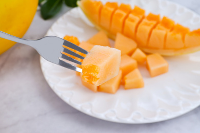 放在盘子里用叉子叉起来的甜瓜果肉块