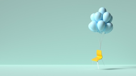 绑在气球上的椅子在柔色背景前