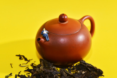 黄色背景上的茶叶茶壶和微缩小人场景