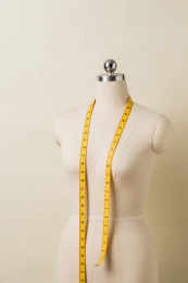 浅棕色背景前，挂着皮尺的立裁人台模特架子