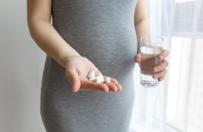 一位年轻孕妇手里拿着钙片和一杯水