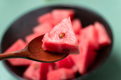 木汤匙盛装的一块三角形西瓜肉特写