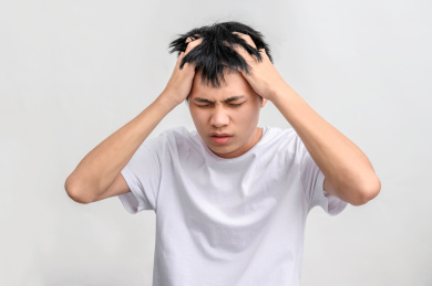 白色背景前难受捂头的年轻人