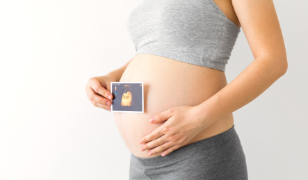 一位年轻孕妇手拿着一张胎儿B超照