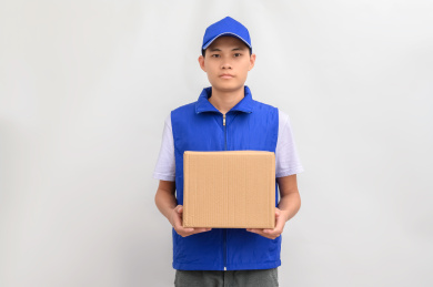白色背景前拿着包裹的快递配送员
