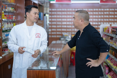 药店里一中年男性与身穿白大褂的人员在交谈