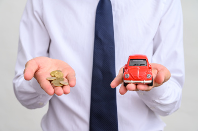 拿着小汽车和硬币的商务人士