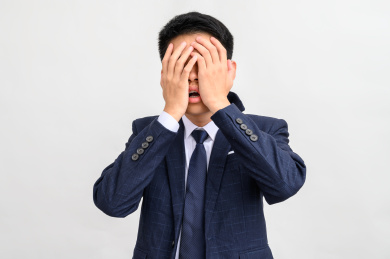 白色背景前捂脸的商务男性