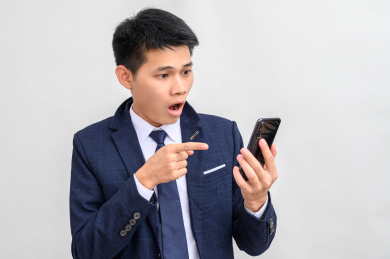 白色背景前看手机惊讶的商务男性