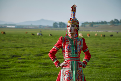 草原上穿着蒙古族传统服饰的亚洲年轻女性
