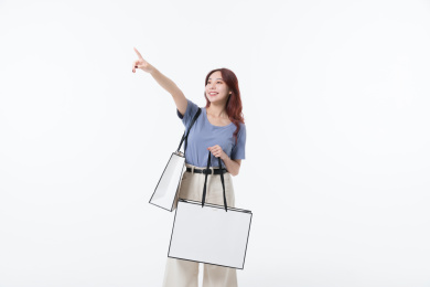 年轻女孩提着购物袋手指前方