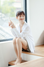 在窗边使用手机的年轻女性