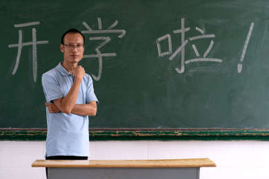 中年男教师在写着"开学啦"的黑板前的肖像