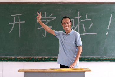 中年男教师在写着"开学啦"的黑板前的肖像