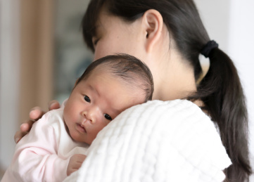 依偎在妈妈怀抱拍嗝的婴儿