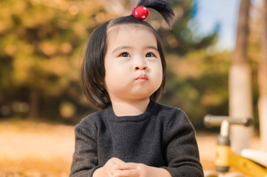 深秋坐在公园落满黄叶的草地上玩耍的女孩