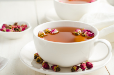 白色茶杯里泡好的玫瑰花茶和干玫瑰花