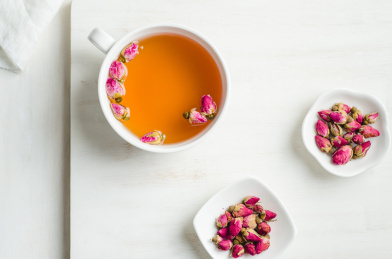 白色茶杯里泡好的玫瑰花茶和干玫瑰花