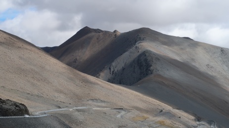 阳光下荒芜山峦中蜿蜒的公路