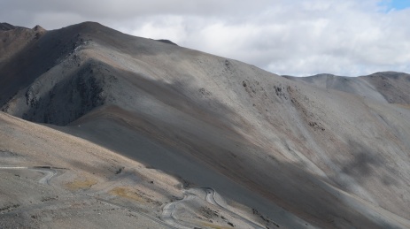阳光下荒芜山峦中蜿蜒的公路