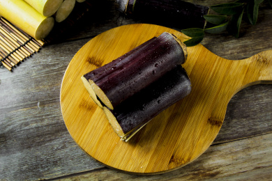 灰底木板上放着一堆黑皮甘蔗