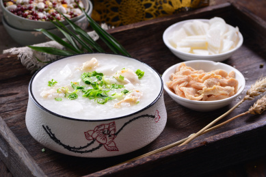 一碗鸡肉山药粥放在木制底板上