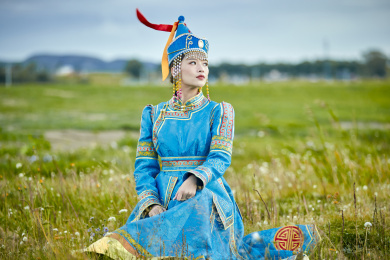 草原上敖包前身穿蒙古族服饰的蒙族少女