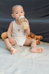 一岁半的男婴儿坐在房间地毯上吃奶