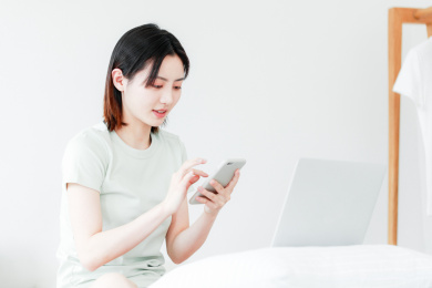 在家使用手机和电脑的年轻东方女性