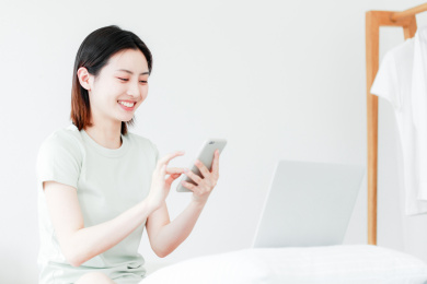 在家使用手机和电脑的年轻东方女性