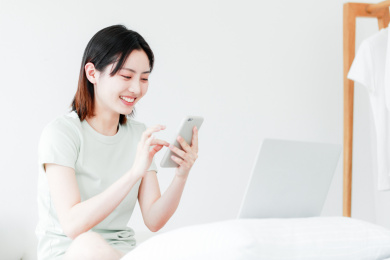 在家使用手机和电脑的年轻东方女性