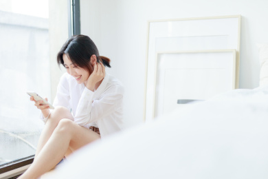 在窗边使用手机的年轻亚洲女性