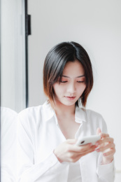 在窗边使用手机的年轻亚洲女性