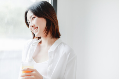 靠在窗边喝果汁的年轻亚洲女性