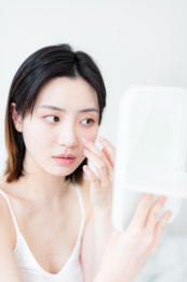 照镜子化妆的年轻东方女性