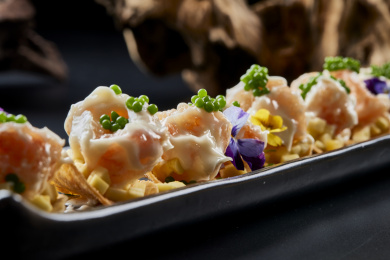 黑色长瓷盘装的青鱼子奶香芝士薯片焗虾仁