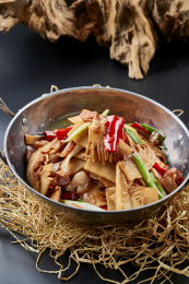 黑色背景上的锅仔香辣腊肉煲鲜笋